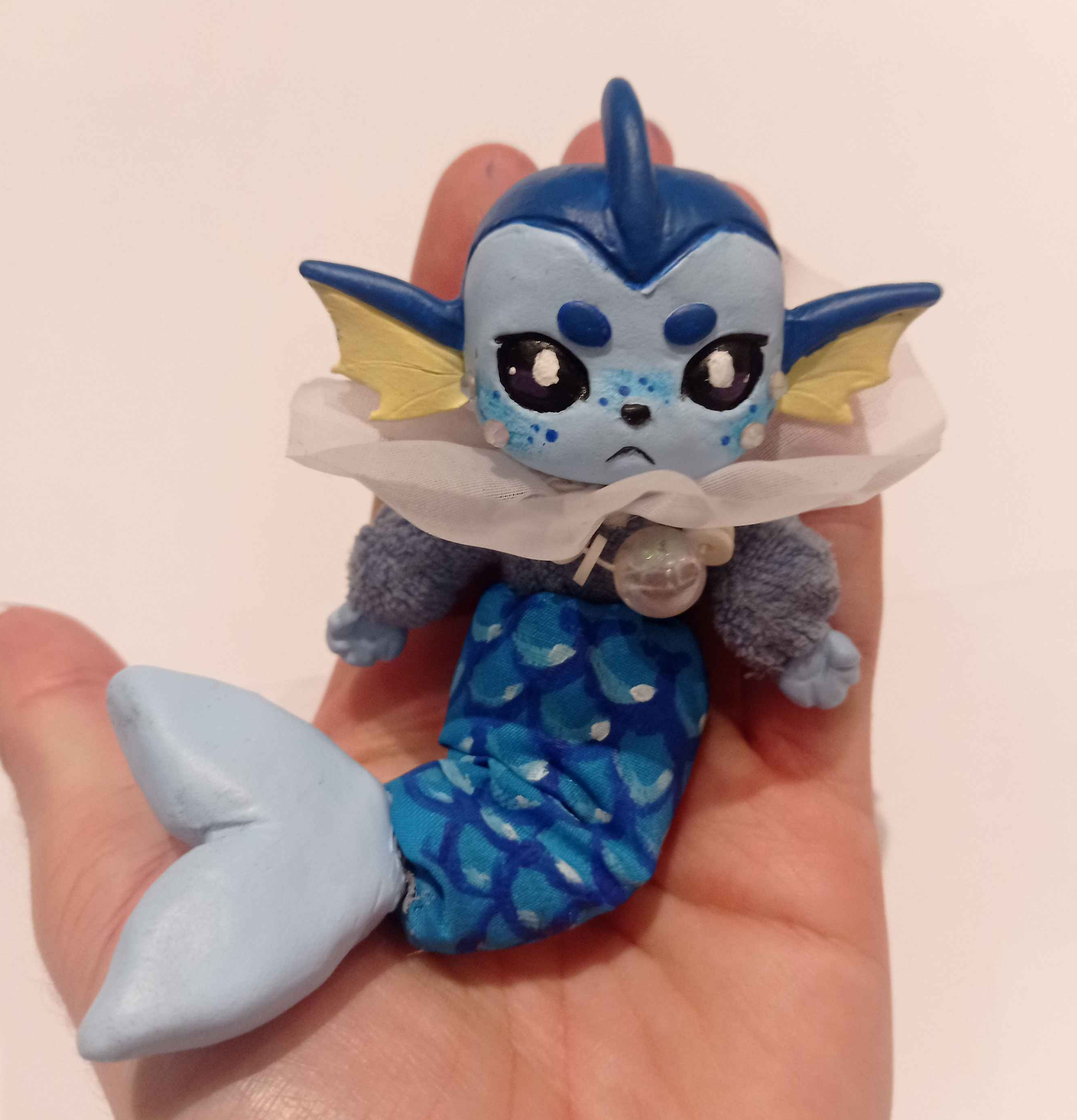 Hand size sculpture of a humanoid with aquatic features. The body is sewn with cloth