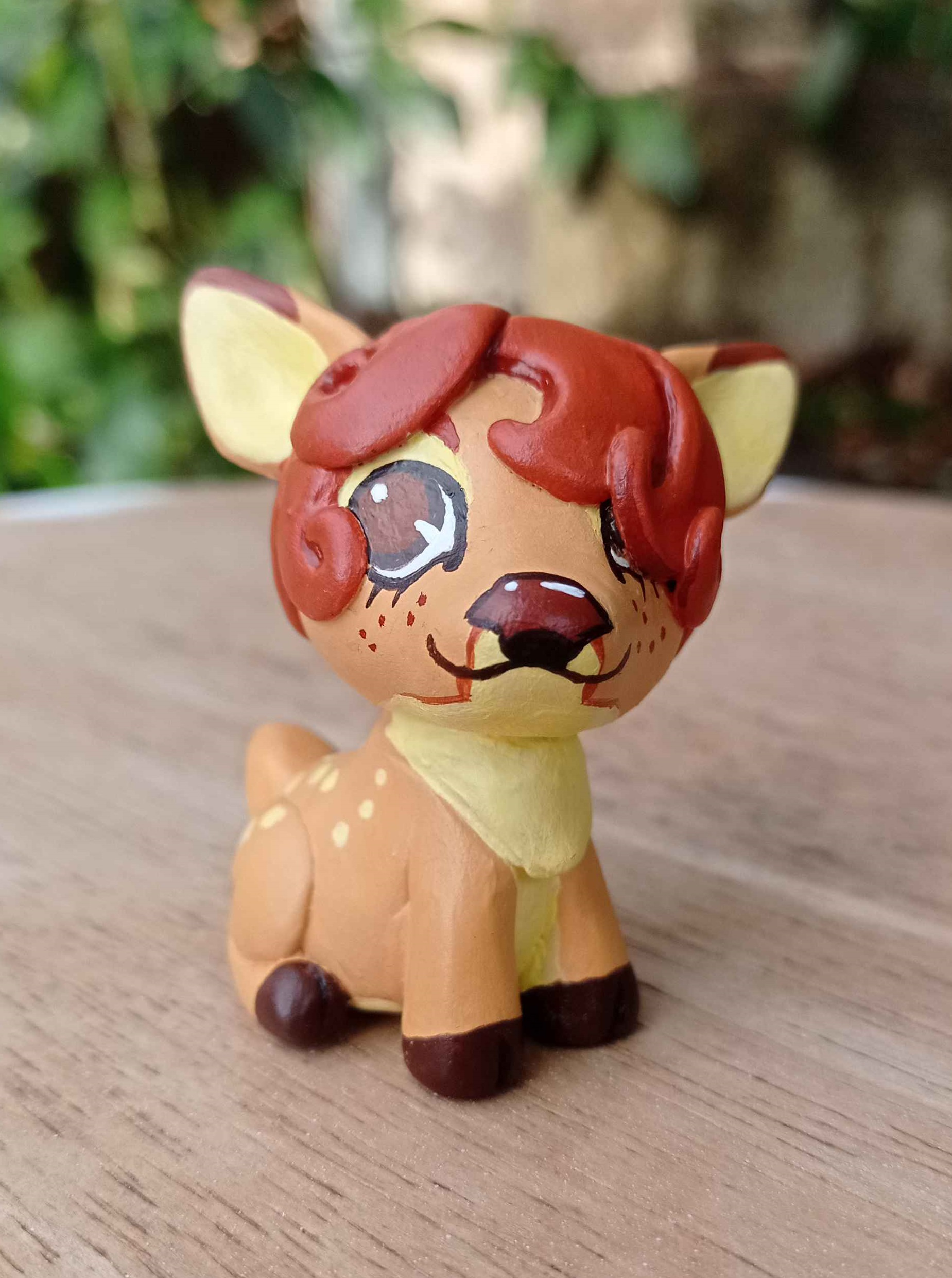 Tiny hand-made sculpture of a yellow and brown deer