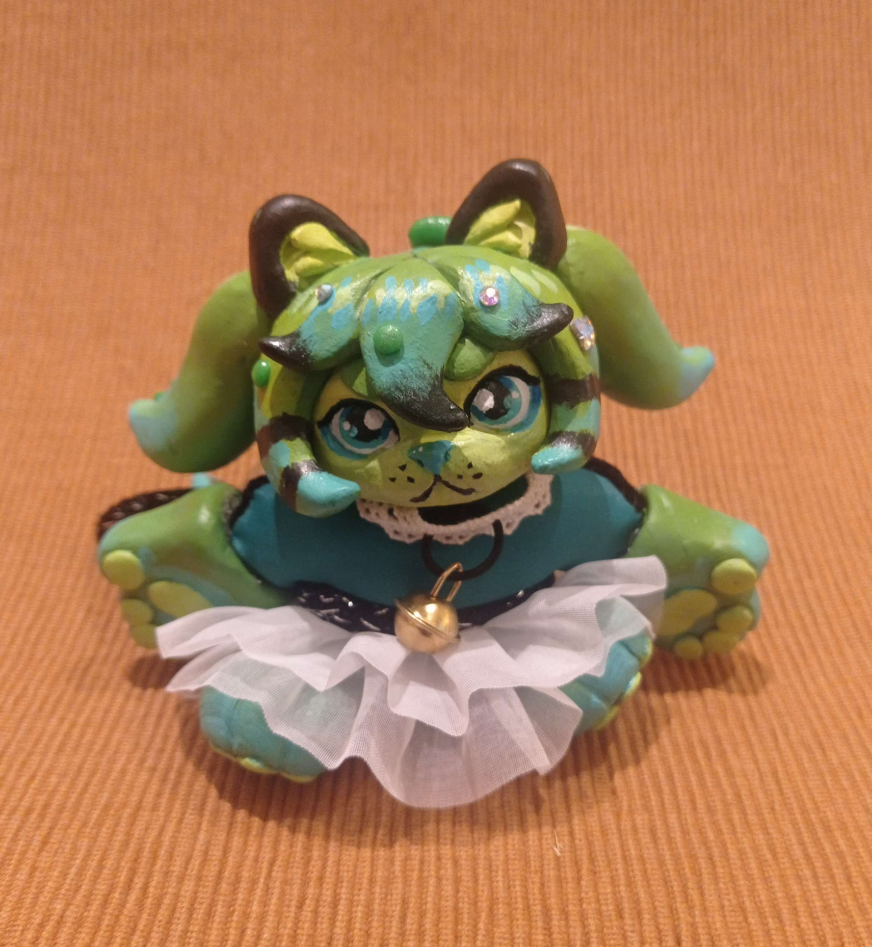 Hand size sculpture of a anthropomorphic cat with green hair