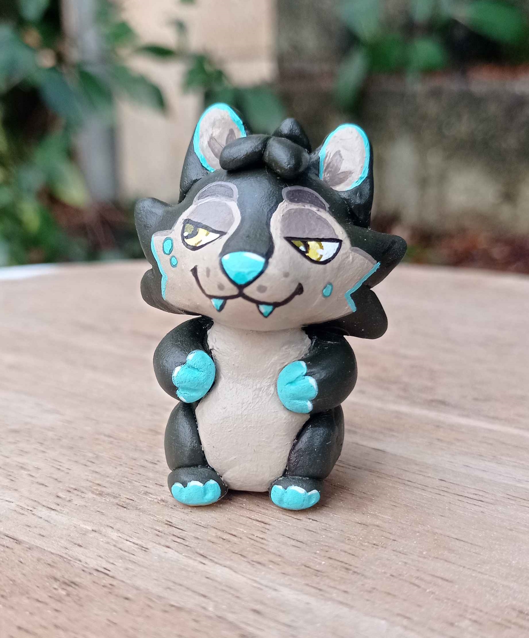 Tiny hand-made sculpture of a dark gray wolf with blue paws